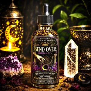 Könnte beinhalten: Eine Glasflasche Bend Over Ritual Oil mit schwarzer Pipette. Das Etikett zeigt Text und Illustrationen in Gold, Lila und Schwarz. Die Flasche enthält 29.57 ml Öl und ist handgefertigt mit traditionellen Zutaten.