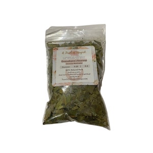 May include: A clear plastic bag filled with dried green Guanabana (Soursop) leaves. The bag has a label with the text "A Touch of Magick" and details about the product, including the weight in ounces and the website address.