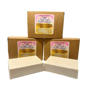 May include: Three rectangular bars of handmade soap, light beige in colour, displayed in front of three brown cardboard boxes. Each box has a label that reads "Daily Spiritual Purification". The soap bars are approximately 10 cm long.