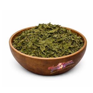 May include: A wooden bowl filled with dried green leaves. The bowl has a natural wood grain and a logo that reads "Touch of Magick" in a cursive font. The leaves appear to be herbs or spices.