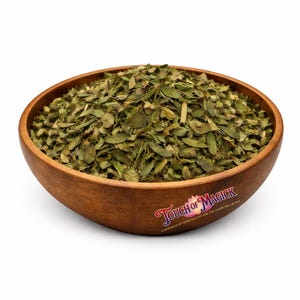 May include: A wooden bowl filled with dried green leaves. The bowl has a natural wood grain and is labeled "Touch of Magick". The leaves are a mix of light and dark green, with a slightly textured appearance.