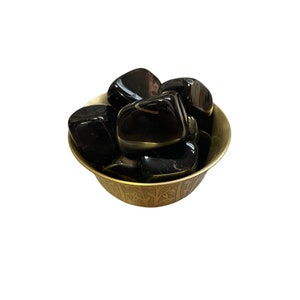 May include: A small bowl made of brass with a decorative design holds several black tumbled stones. The bowl is filled with black obsidian stones.