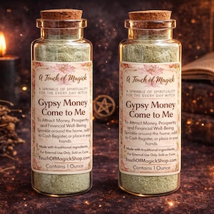 May include: Two glass bottles with cork stoppers, filled with green powder. Each bottle has a label that reads "A Touch of Magick" and "Gypsy Money Come to Me." The background includes candles and a book.