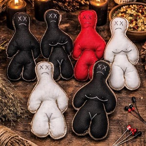 Può includere: Una collezione di bambole voodoo fatte a mano in nero, rosso e bianco, disposte su una superficie di legno rustico. Ogni bambola ha tratti del viso cuciti e una forma del corpo semplice. La scena include candele, erbe secche e un teschio.