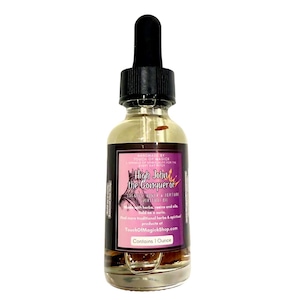 May include: A clear glass bottle with a black dropper top, containing a golden liquid. The label reads "High John the Conqueror" and "Contains 1 Ounce". The label is purple and pink with white text. The bottle is against a white background.