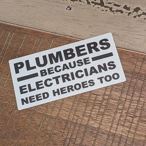 May include: White sticker with black text that reads "Plumbers because electricians need heroes too".