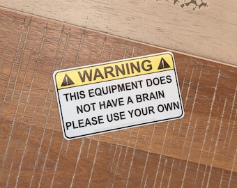 Warning This Equipment Does Not Have A Brain Please Use Your Own Sticker - Decal - Vinyl with Gloss Laminate