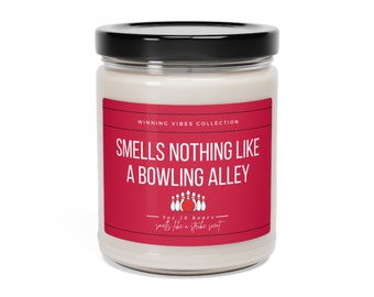 May include: A glass candle jar with a black lid. The label is red and says "WINNING VIBES COLLECTION SMELLS NOTHING LIKE A BOWLING ALLEY" with a bowling pin graphic and the text "9 oz. 30 hours smells like a strike scent".
