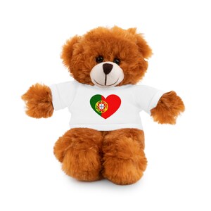 May include: A brown teddy bear wearing a white t-shirt with a red heart featuring the Portuguese flag.