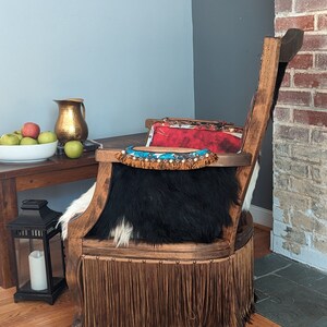Elevate your farmhouse decor with this stunning Western Style Brown Leather Chair, a perfect blend of rustic charm and vintage appeal. Crafted from reclaimed wood and upcycled materials, this unique piece features a distressed brown leather frame that exudes cowboy cool. The upholstery is adorned with a striking Highland cow print, adding a touch of countryside authenticity, while the goat-skin hides drape gracefully over the seat, offering both comfort and texture.