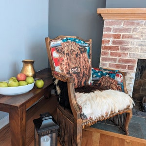 Elevate your farmhouse decor with this stunning Western Style Brown Leather Chair, a perfect blend of rustic charm and vintage appeal. Crafted from reclaimed wood and upcycled materials, this unique piece features a distressed brown leather frame that exudes cowboy cool. The upholstery is adorned with a striking Highland cow print, adding a touch of countryside authenticity, while the goat-skin hides drape gracefully over the seat, offering both comfort and texture.