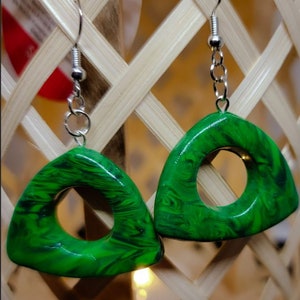 May include: A pair of green triangle-shaped earrings with a swirl pattern and a circular opening in the center. The earrings are made of polymer clay and have silver hooks.