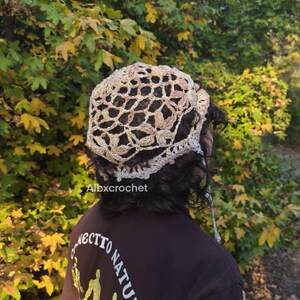 Puede incluir: Un sombrero de ganchillo en tonos beige y marr&oacute;n claro, con un dise&ntilde;o calado. El sombrero lo lleva una persona con cabello oscuro. El texto "Albxcrochet" es visible. La persona lleva una camiseta marr&oacute;n oscuro con el texto "NECTTO NATURE".