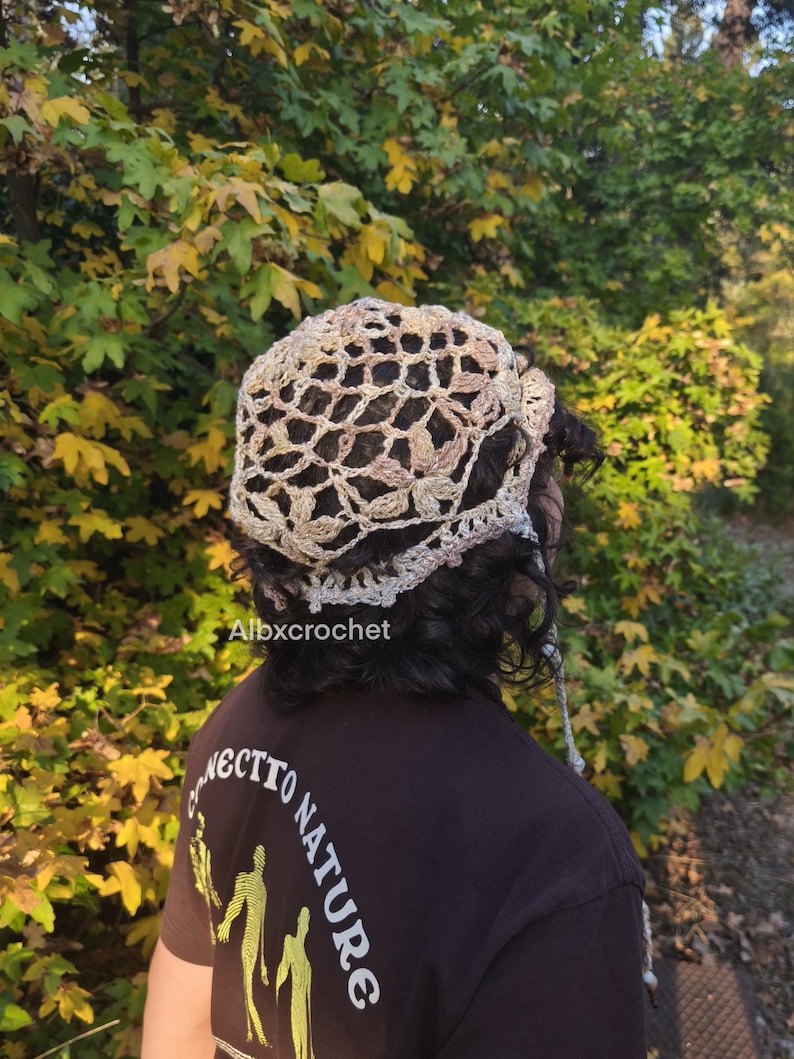 Puede incluir: Un sombrero de ganchillo en tonos beige y marr&oacute;n claro, con un dise&ntilde;o calado. El sombrero lo lleva una persona con cabello oscuro. El texto "Albxcrochet" es visible. La persona lleva una camiseta marr&oacute;n oscuro con el texto "NECTTO NATURE".