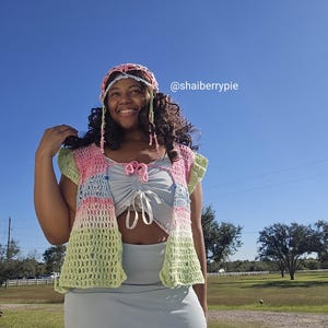 Puede incluir: Un conjunto de crochet colorido con chaleco, diadema y top. El chaleco tiene una combinaci&oacute;n de colores pastel de rosa, azul y verde. La diadema coincide con los colores del chaleco. El top y la falda son de color azul claro.