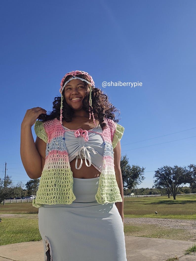 Puede incluir: Un conjunto de crochet colorido con chaleco, diadema y top. El chaleco tiene una combinaci&oacute;n de colores pastel de rosa, azul y verde. La diadema coincide con los colores del chaleco. El top y la falda son de color azul claro.