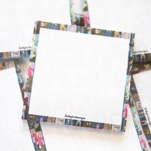 May include: Square white notepads with a patterned border featuring figures in various colors. The notepads are stacked and slightly overlapping. The text "Arbtytreedesigns" is printed on the bottom of the notepad.