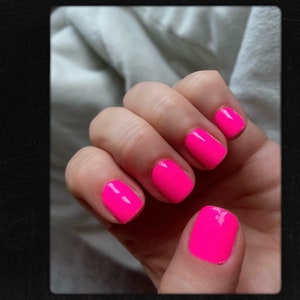 May include: Close-up of a hand with bright pink nail polish on all five fingernails.