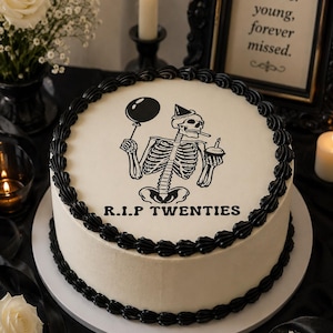 Peut inclure: Un gâteau rond blanc avec des bordures de glaçage noir sur les bords supérieur et inférieur. Le centre présente un graphique noir d'un squelette portant un chapeau de fête, tenant un ballon et un cupcake, avec le texte R.I.P TWENTIES imprimé.