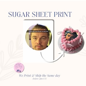 May include: A pink heart-shaped cake with a photo of a man on top, decorated with pink frosting and white ribbons. The image also includes a graphic with the text "SUGAR SHEET PRINT" and a photo of the same man.