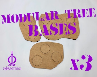 Op de afbeelding: Drie modulaire boomvoeten van bruin hout, elk met cirkelvormige uitsparingen. De tekst "MODULAR TREE BASES" en "x3" zijn paars. Het Norseman-logo is ook paars.