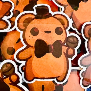 May include: A set of brown bear stickers with black bow ties. The bears are wearing hats and holding a microphone. The stickers are on a blue background.