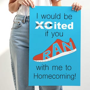 Puede incluir: Un póster azul con el texto "I would be XCited if you RAN with me to Homecoming!" presenta un gráfico de zapatilla para correr roja con la palabra "RAN" en azul. El póster lo sostiene una persona que lleva una camisa blanca y vaqueros azules.