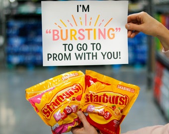 Peut inclure: Une carte blanche avec le texte "I'm "BURSTING" to go to prom with you!" avec un motif de soleil jaune. Deux sacs de bonbons Starburst sont au premier plan.