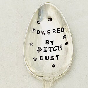 May include: A silver spoon with the text "Powered by Bitch Dust" engraved on it.