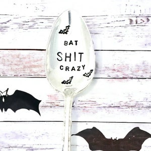 May include: A silver spoon with the text "Bat Shit Crazy" and bat silhouettes engraved on it.