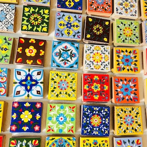 Puede incluir: Una colección de baldosas cuadradas coloridas con intrincados diseños florales. Las baldosas presentan una variedad de colores, incluyendo amarillo, azul, rojo y verde, con diseños detallados. Las baldosas están dispuestas juntas, mostrando los diversos patrones.