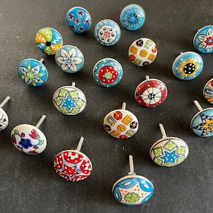 May include: Assortment of 18 colorful ceramic drawer knobs with various geometric and floral patterns. The knobs are blue, green, red, yellow, and white.