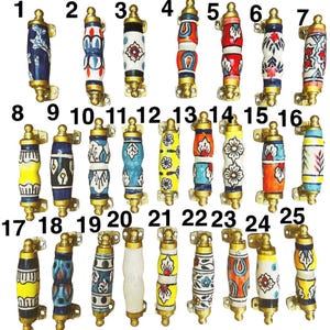 Könnte beinhalten: Eine Sammlung von 25 dekorativen Keramik-Schrankgriffen mit Messingbeschlägen. Jeder Griff hat ein einzigartiges handgemaltes Design in verschiedenen Farben, darunter Blau, Gelb, Rot und Weiß. Die Griffe sind ca. 10 cm lang.