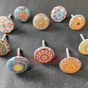 May include: Nine colorful ceramic cabinet knobs with intricate mandala designs. Each knob features a different pattern with shades of blue, orange, red, yellow, and green.