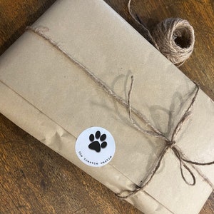 May include: A brown paper package tied with twine and a white sticker with a black paw print and the text "the toastle weetie".