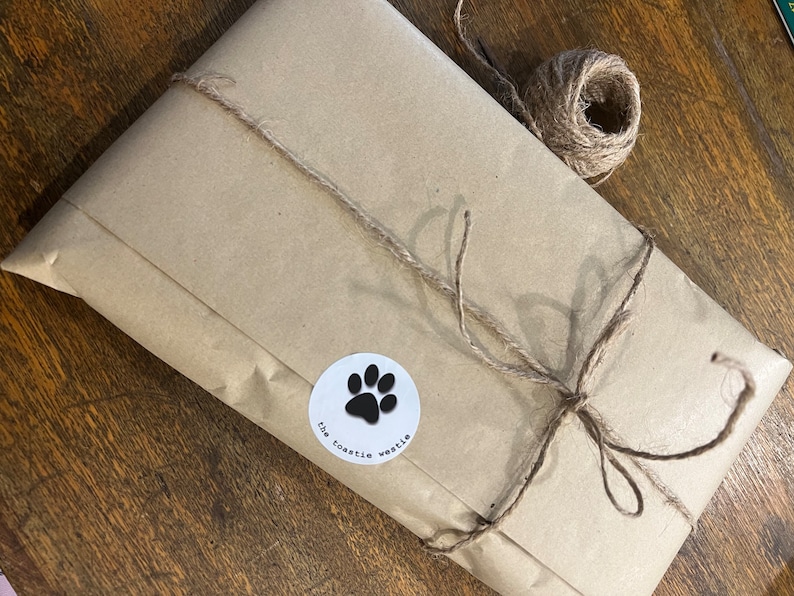 May include: A brown paper package tied with twine and a white sticker with a black paw print and the text "the toastle weetie".