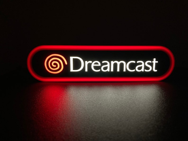 May include: A red and white sign with the text "Dreamcast" and a stylized red swirl logo.