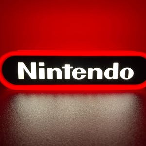 Puede incluir: Un letrero rojo y negro con la palabra "Nintendo" en letras blancas.