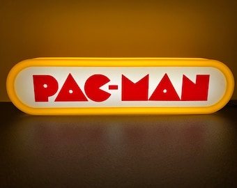 May include: A yellow and white sign with the word "PAC-MAN" in red letters.