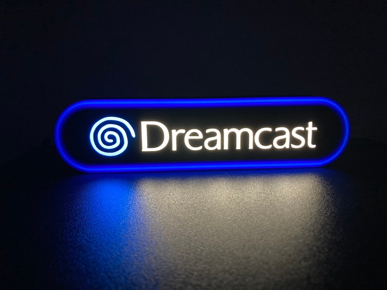 May include: A blue and white neon sign with the text "Dreamcast" and a stylized logo.