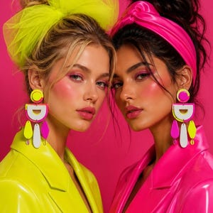 May include: A pair of neon yellow tulle hair accessories and a bright pink knotted headband. The earrings feature geometric shapes in neon yellow, white, and hot pink, with dangling teardrop and oval pendants. The clothing consists of neon yellow and hot pink blazers.