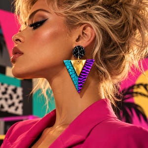Peut inclure: Une boucle d'oreille imposante composée d'un clou circulaire à motif marbre noir relié à un grand pendentif triangulaire. Le pendentif est divisé en trois sections : un côté turquoise texturé, un triangle central doré et un côté rayé violet.