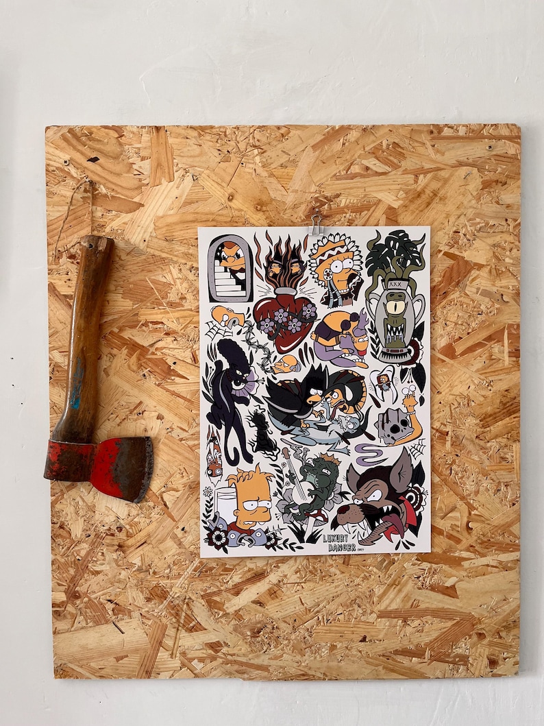 K&ouml;nnte beinhalten: Eine Axt mit Holzgriff und roter Klinge neben einem Stickerbogen mit verschiedenen Illustrationen im Cartoon-Stil. Der Stickerbogen enth&auml;lt Bilder von Charakteren und Objekten im Tattoo-Stil.