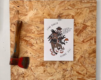 May include: Axe with a wooden handle and a red blade, mounted on a wooden board. A print with the text "LONE RANGER" and "LUX DANGER" depicts a cowboy riding a horse. The print is attached with a clip.