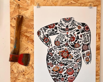 May include: A print of a female form, adorned with a floral pattern in red, orange, and black, is displayed on a wooden board. The print is held by silver clips. An axe with a wooden handle and red blade is mounted on the board.