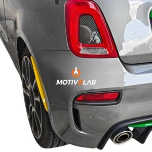 Pode incluir: Parte traseira de um carro cinza com uma luz traseira vermelha e um detalhe amarelo. O carro tem uma roda preta e um escapamento cromado. O texto "MOTIV LAB" é visível.