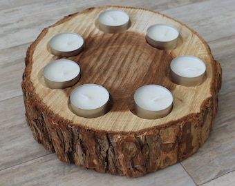 May include: A wooden candle holder made from a tree trunk slice with seven circular cutouts for tealight candles. The candle holder is brown and has a natural bark texture.