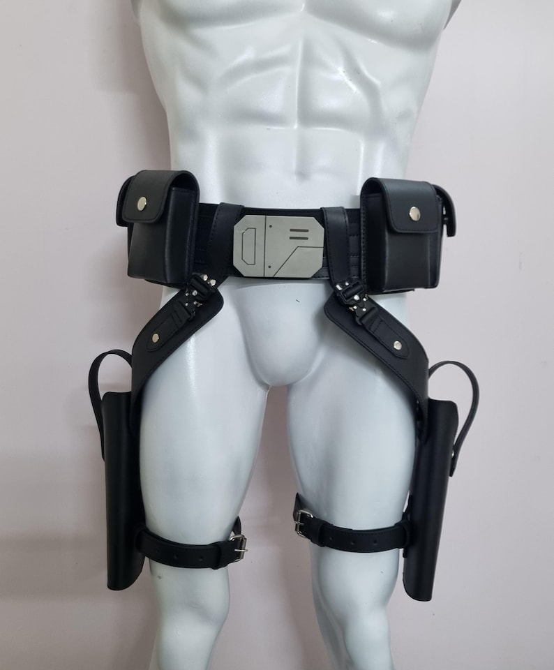 May include: A black utility belt featuring two rectangular pouches with silver snap closures, a central metallic buckle with geometric engravings, and two drop-leg holsters attached to adjustable thigh straps with silver metal buckles.