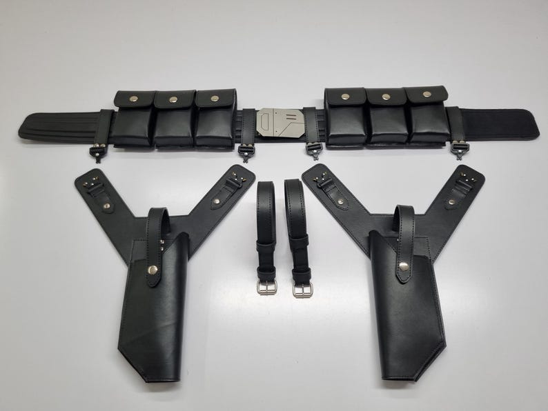 May include: A black utility belt featuring six rectangular pouches with snap closures and a central metallic buckle. Below the belt are two black holster attachments with Y-shaped straps and two separate black adjustable straps with metal buckles.