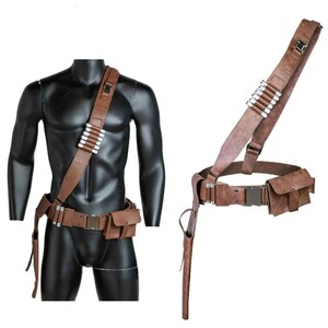 May include: A brown leather belt with a holster and a shoulder strap. The belt has a silver buckle and a pouch on the right side. The shoulder strap has a silver buckle and a pouch on the left side.